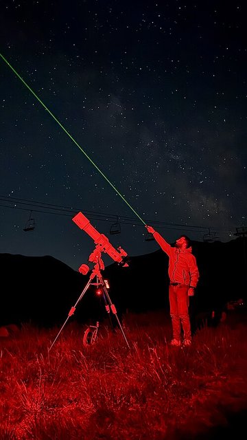 Люди наблюдают звёздное небо через телескоп-рефрактор вдали от городских огней