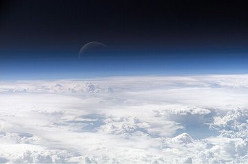 Вид с орбиты: облака, над ними тонкая голубая полоса атмосферы и чернота космоса