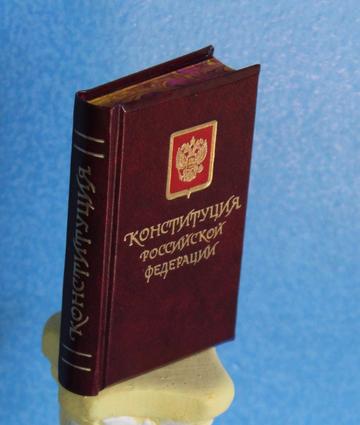 Небольшая книга в тёмно-красном переплёте с золотым гербом России и надписью «Конституция Российской Федерации»