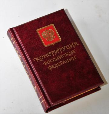 Книга в тёмно-красном переплёте с золотым гербом России и надписью «Конституция Российской Федерации»