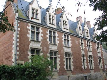 Длинное двухэтажное здание из красного кирпича с белыми каменными углами и рамами окон; на высокой тёмной крыше стоят белые слуховые окна с острыми треугольными верхушками